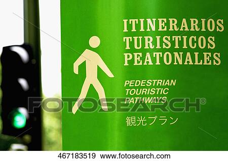 Stock Photo - Close-up of a pedestrian walkway sign with a traffic light in the background, Madrid, Spain. Fotosearch