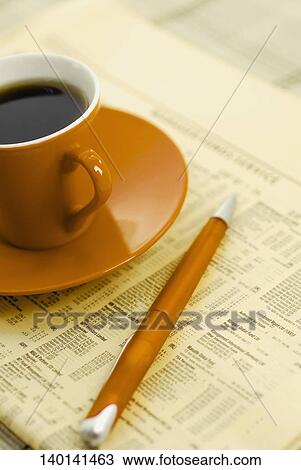 Stock Image - Close-up of a pen and tea cup on a financial newspaper. Fotosearch