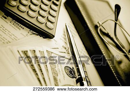 Stock Photograph - Close-up of a pen with a calculator and eyeglasses on a financial newspaper. Fotosearch
