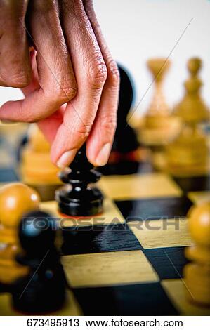 Stock Image - Close-up of a person's hand holding a chess piece. Fotosearch