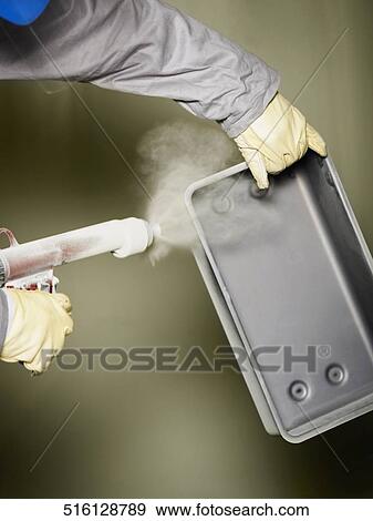 Close-up of a person's hand spraying paint on a metal object View Large Photo Image Stock Photo - Close-up of a person's hand spraying paint on a metal object. Fotosearch