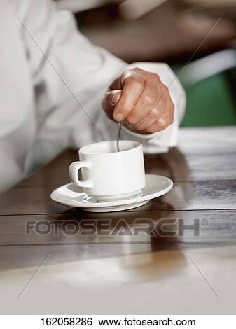 Close-up of a person's hand stirring coffee View Large Photo Image Stock Photograph - Close-up of a person's hand stirring coffee. Fotosearch