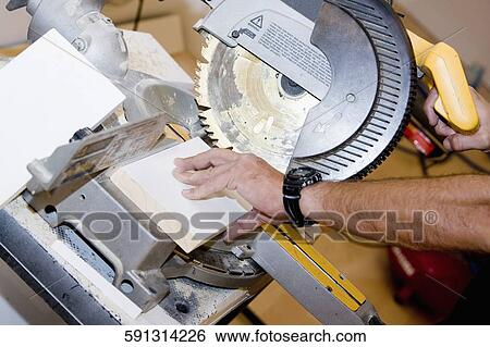 Stock Photograph - Close-up of a person's hand using a circular saw. Fotosearch