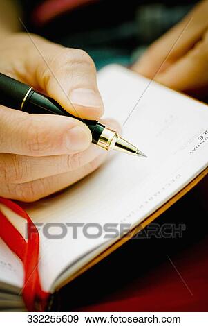 Close-up of a person's hand writing on a diary View Large Photo Image Stock Photo - Close-up of a person's hand writing on a diary. Fotosearch