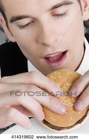 Stock Image - Close-up of a waiter eating a burger. Fotosearch