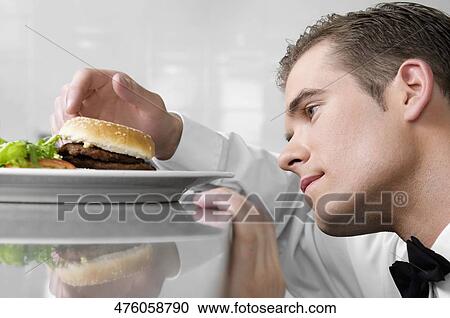 Stock Image - Close-up of a waiter holding a burger. Fotosearch