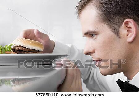 Stock Image - Close-up of a waiter holding a burger. Fotosearch