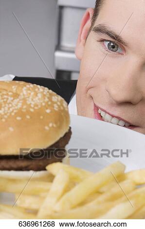 Close-up of a waiter looking at a burger and smiling View Large Photo Image Stock Photo - Close-up of a waiter looking at a burger and smiling. Fotosearch