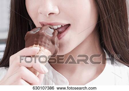 Close-up of a woman eating an ice cream View Large Photo Image Stock Photograph - Close-up of a woman eating an ice cream. Fotosearch