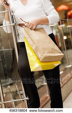 Close-up of a woman holding a mobile phone and sunglasses with shopping bags View Large Photo Image Picture - Close-up of a woman holding a mobile phone and sunglasses with shopping bags. Fotosearch