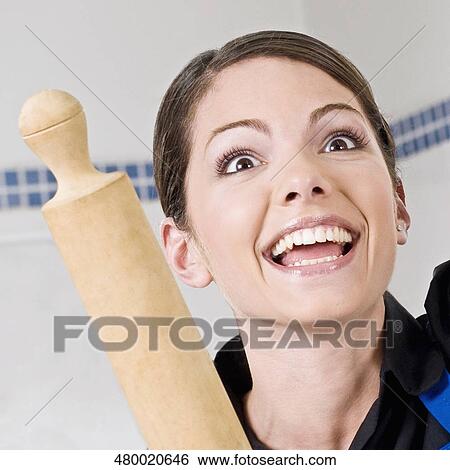 Stock Photograph - Close-up of a woman holding a rolling pin and laughing. Fotosearch