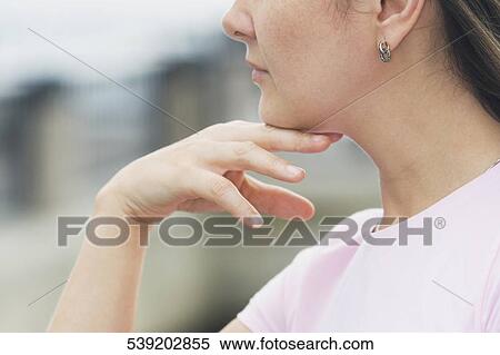 Close-up of a young woman thinking with her hand on her chin View Large Photo Image Stock Photography - Close-up of a young woman thinking with her hand on her chin. Fotosearch