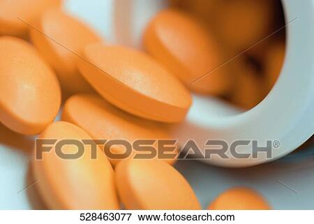 Stock Photo - Close-up of pills spilling out from a pill bottle. Fotosearch