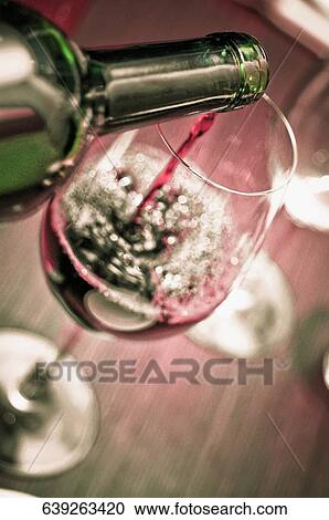 Stock Image - Close-up of red wine being poured in a wine glass. Fotosearch