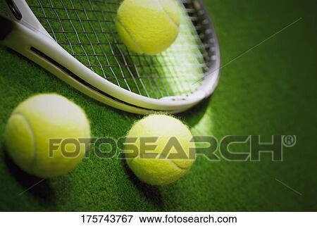Close-up of three tennis balls with a tennis racket in a court View Large Photo Image Stock Photo - Close-up of three tennis balls with a tennis racket in a court. Fotosearch