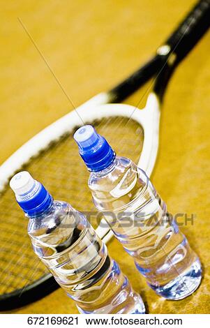Stock Image - Close-up of two water bottles and a tennis racket. Fotosearch