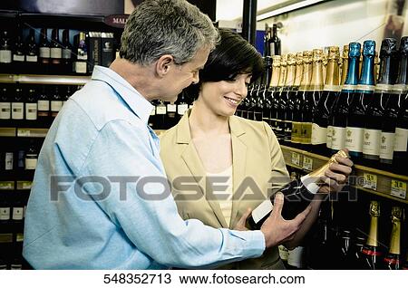 Couple buying a wine in a supermarket View Large Photo Image Stock Image - Couple buying a wine in a supermarket. Fotosearch