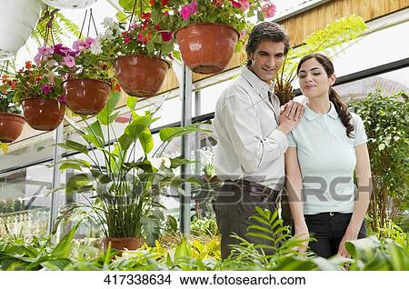 Picture - Couple choosing plants in a greenhouse. Fotosearch