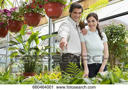 Stock Image - Couple choosing plants in a greenhouse. Fotosearch