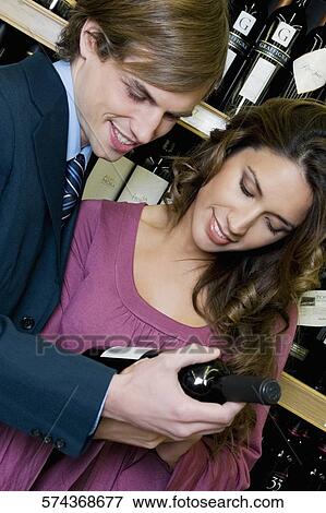 Couple choosing wine bottle in a liquor store View Large Photo Image Stock Photo - Couple choosing wine bottle in a liquor store. Fotosearch