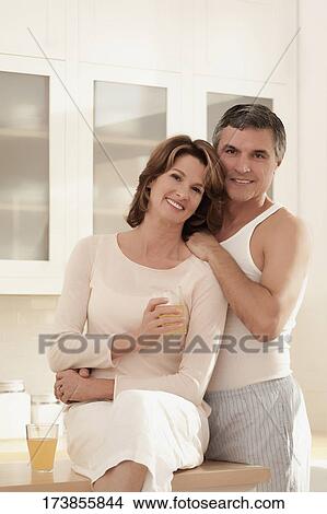 Couple drinking juice and romancing in the kitchen View Large Photo Image Picture - Couple drinking juice and romancing in the kitchen. Fotosearch