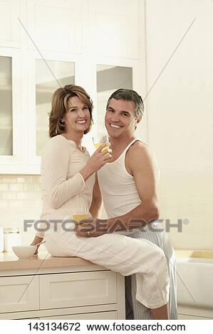 Couple drinking juice and romancing in the kitchen View Large Photo Image Stock Image - Couple drinking juice and romancing in the kitchen. Fotosearch