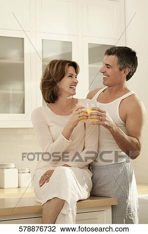 Couple drinking juice and romancing in the kitchen View Large Photo Image Stock Image - Couple drinking juice and romancing in the kitchen. Fotosearch