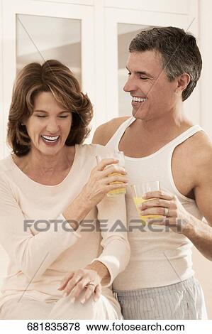 Couple drinking juice and romancing in the kitchen View Large Photo Image Stock Photo - Couple drinking juice and romancing in the kitchen. Fotosearch