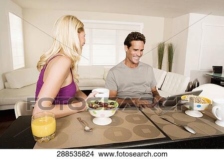 Couple having breakfast and using a laptop View Large Photo Image Picture - Couple having breakfast and using a laptop. Fotosearch