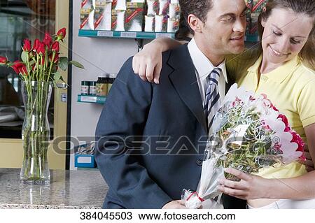 Stock Image - Couple holding a bouquet of flowers in a flower shop. Fotosearch