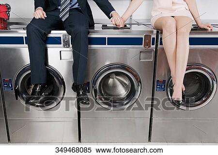 Couple holding hands and sitting on washing machines View Large Photo Image Stock Photography - Couple holding hands and sitting on washing machines. Fotosearch