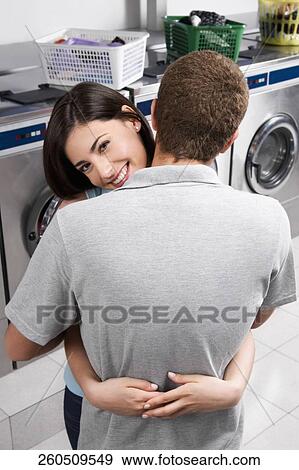 Couple hugging in a laundromat View Large Photo Image Stock Photo - Couple hugging in a laundromat. Fotosearch