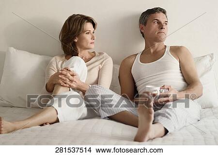 Couple looking serious on the bed View Large Photo Image Picture - Couple looking serious on the bed. Fotosearch