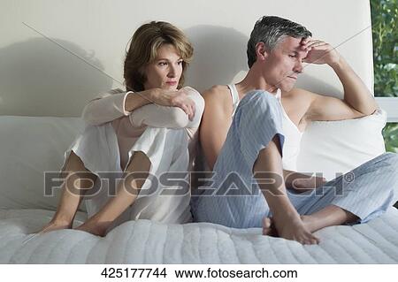 Couple looking serious on the bed View Large Photo Image Picture - Couple looking serious on the bed. Fotosearch