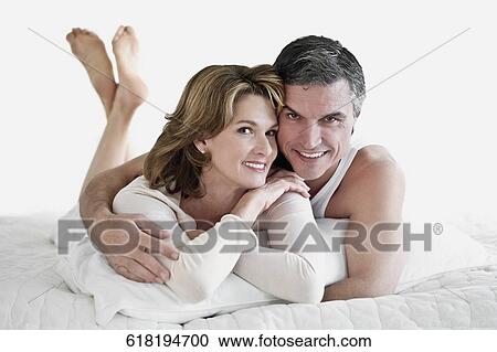 Stock Image - Couple lying on the bed and smiling. Fotosearch