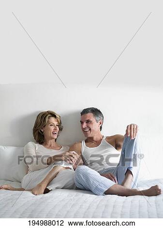 Couple reclining on the bed and talking to each other View Large Photo Image Stock Image - Couple reclining on the bed and talking to each other. Fotosearch