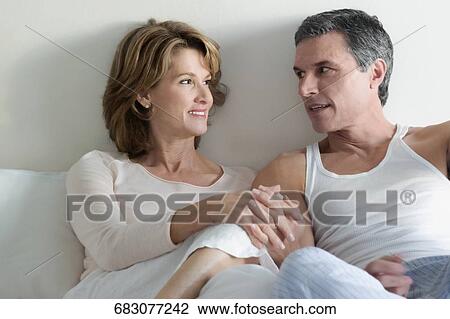 Couple reclining on the bed and talking to each other View Large Photo Image Stock Image - Couple reclining on the bed and talking to each other. Fotosearch