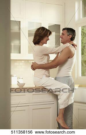 Stock Photograph - Couple romancing in the kitchen. Fotosearch