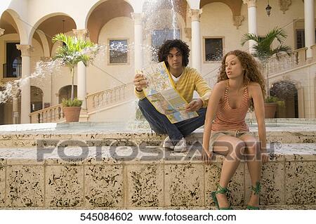 Couple sitting near a fountain and holding a map, Biltmore Hotel, Coral Gables, Florida, USA View Large Photo Image Stock Image - Couple sitting near a fountain and holding a map, Biltmore Hotel, Coral Gables, Florida, USA. Fotosearch