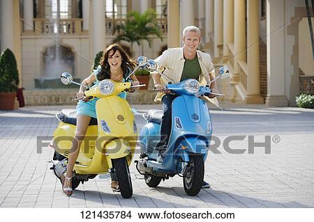 Picture - Couple sitting on mopeds, Biltmore Hotel, Coral Gables, Florida, USA. Fotosearch