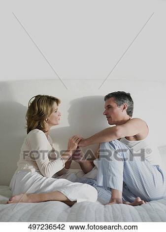 Couple sitting on the bed with holding hands View Large Photo Image Stock Image - Couple sitting on the bed with holding hands. Fotosearch
