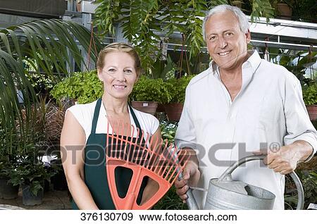 Stock Photo - Couple standing together in a greenhouse and smiling. Fotosearch