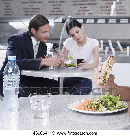 Stock Photo - Couple text messaging on a mobile phone in a restaurant. Fotosearch