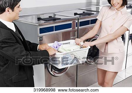 Couple tugging a basket in a laundromat View Large Photo Image Stock Photo - Couple tugging a basket in a laundromat. Fotosearch