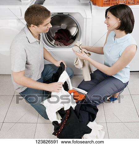 Couple washing clothes in a laundromat View Large Photo Image Stock Image - Couple washing clothes in a laundromat. Fotosearch