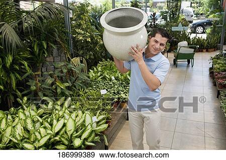 Stock Photo - Customer holding a decorative urn in a greenhouse. Fotosearch