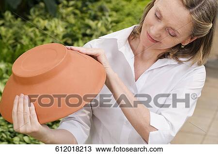 Customer holding earthenware pot in a greenhouse View Large Photo Image Stock Image - Customer holding earthenware pot in a greenhouse. Fotosearch