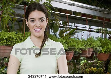 Customer standing in a greenhouse and smiling View Large Photo Image Stock Image - Customer standing in a greenhouse and smiling. Fotosearch