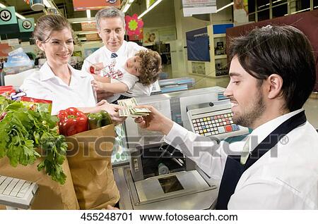 Stock Image - Customers at checkout counter in a supermarket. Fotosearch
