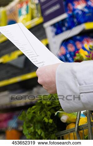 Customer's hands holding a shopping list View Large Photo Image Stock Photo - Customer's hands holding a shopping list. Fotosearch